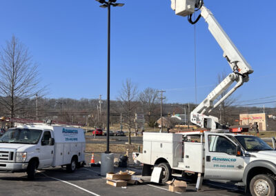 Extended bucket truck performing pole lighting repairs in a commercial parking lot